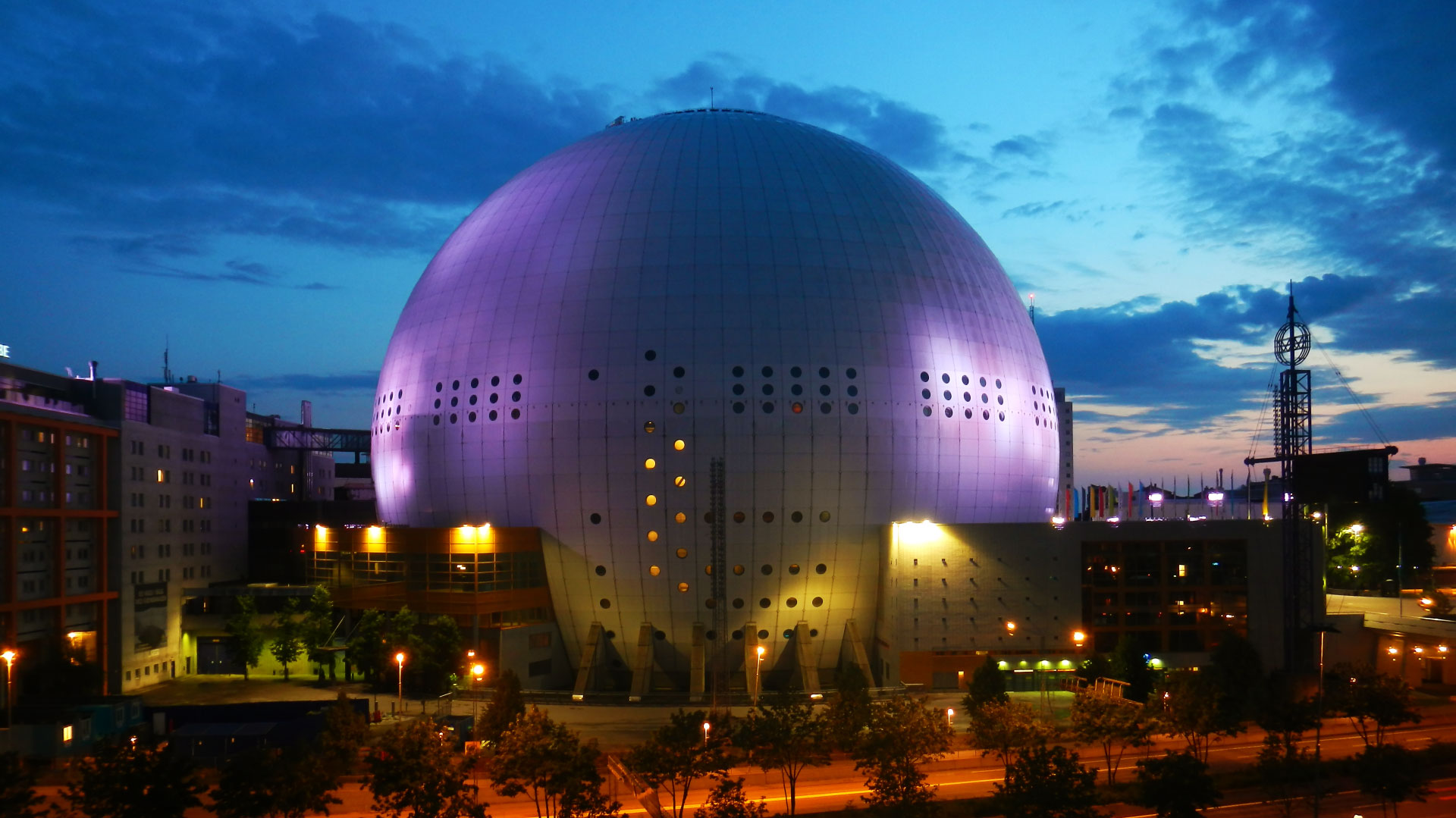 عکس ساختمان گنبدی استادیوم اریکسون در شهر استکهلم در شب با نورپردازی بنفش